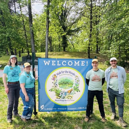 Scenic Rivers Land Trust staff stand in front of the welcome sign at Walk for the Woods 2026.